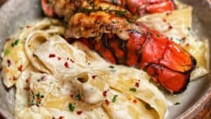 a bowl of pasta with two grilled lobster tails
