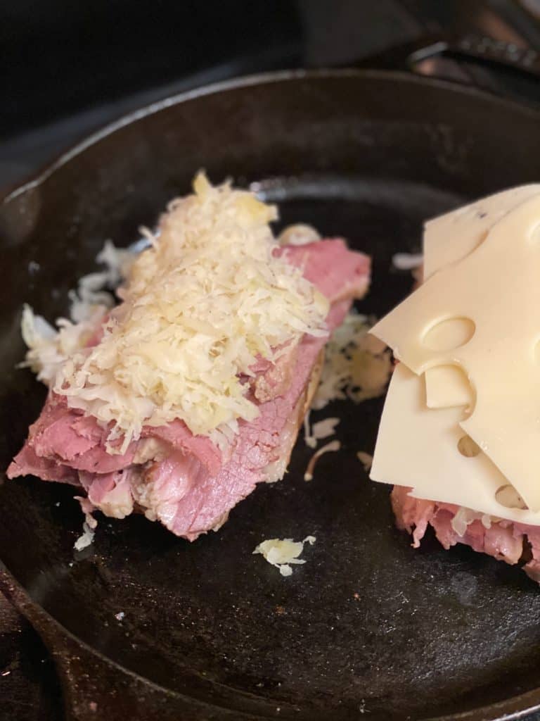 rueben sandwiches grilling in a cast iron pan
