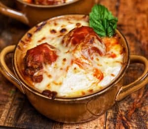 two bowls of baked meatballs with a garnish of basil