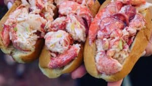 me holding three lobster rolls