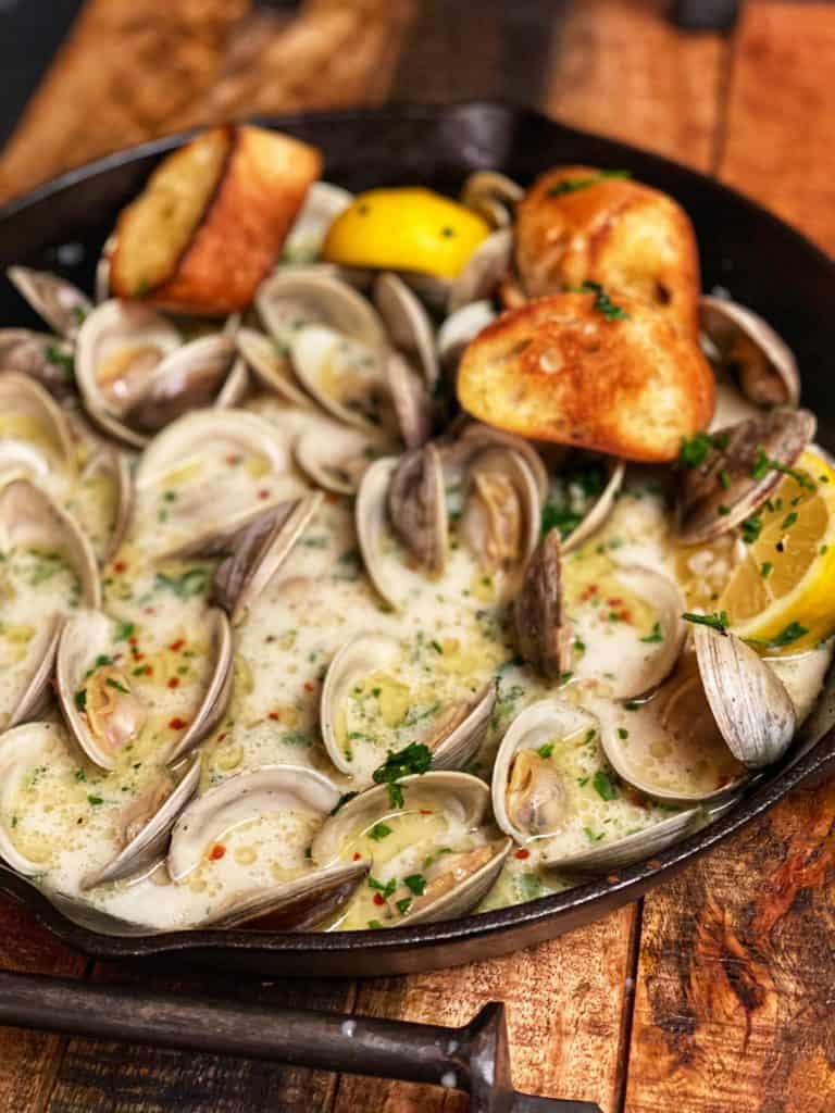 A cast iron pan of butter garlic steamed clams with crusty bread.