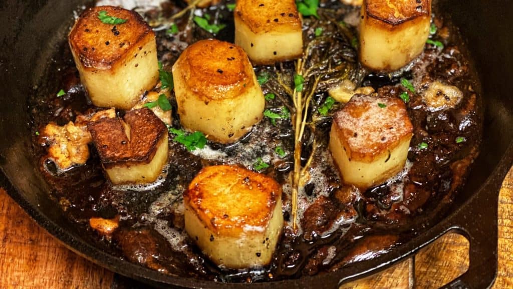 a cast iron skillet of fondant potatoes