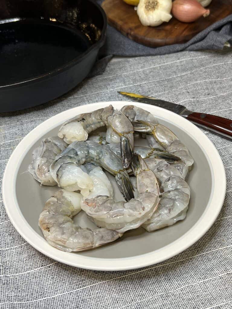 A grey plate with 9 jumbo peeled and deveined shrimp with the tail-on.