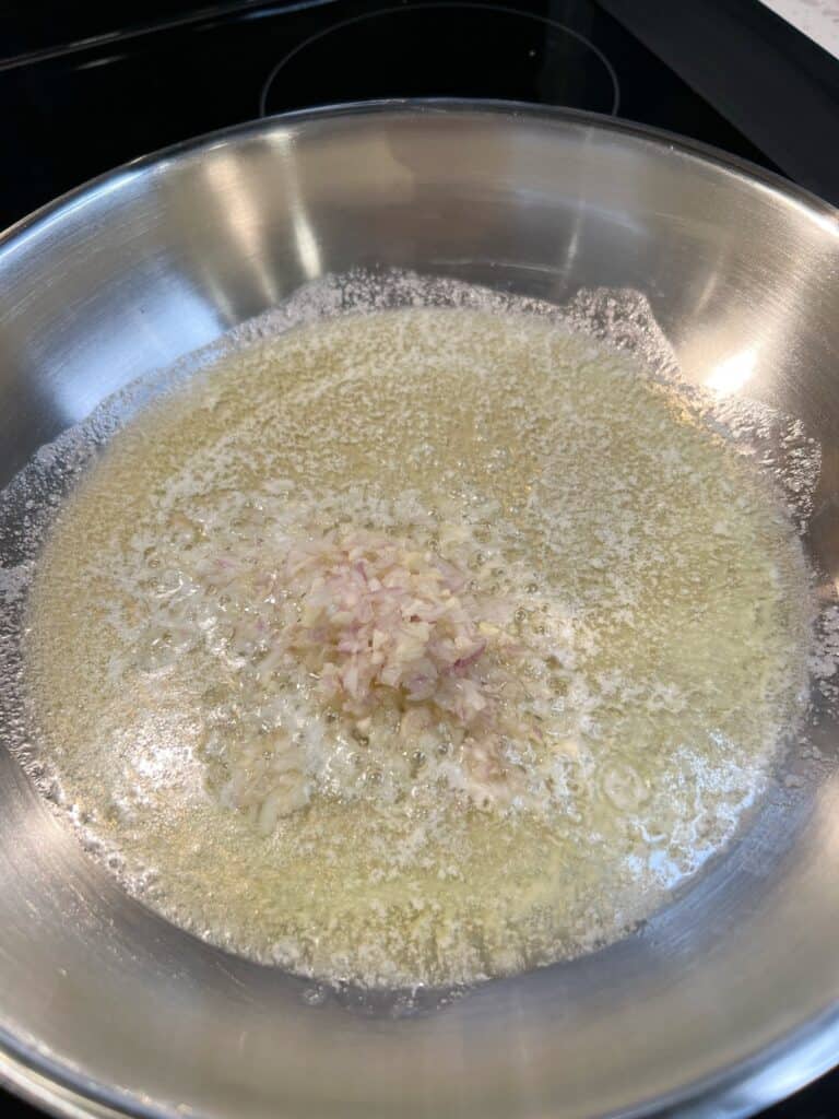 Minced shallots and garlic sautéing in butter for the filling for crab stuffed shrimp
