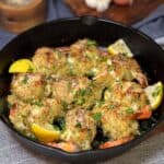 Nine crab stuffed shrimp garnished with fresh parsley and lemon wedges baked to a golden brown in a cast iron pan.