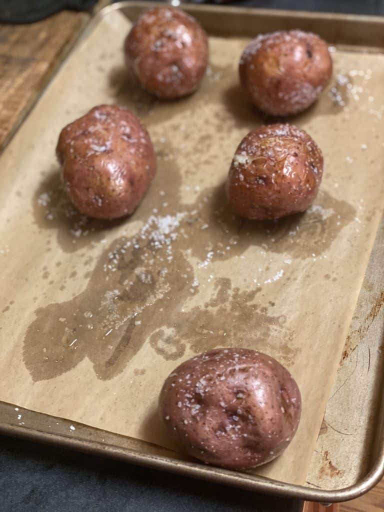 five red potatoes baked on a baking sheet