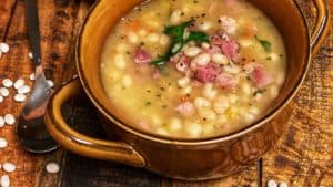 two bowls of navy bean and ham soup on a wooden board