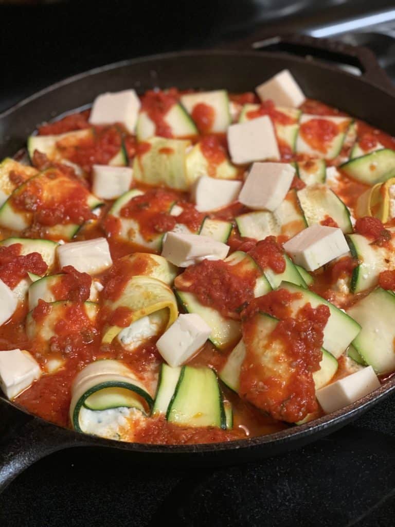 a cast iron pan of zucchini rollatini ready to be baked