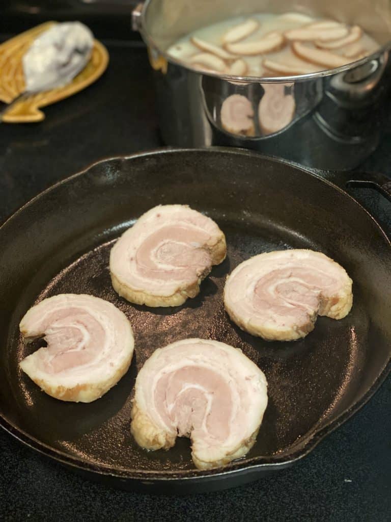 searing pork belly rounds in a cast iron pan