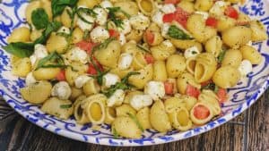 a blue and white bowl filled with caprese pasta salad