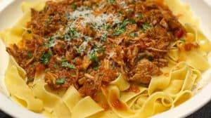Pappardelle in a white bowl topped with pork ragu