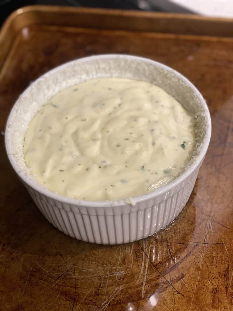 cheese soufflé mixture in a white ramekin ready to bake