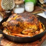 A roasted chicken and vegetables in a cast iron pan.