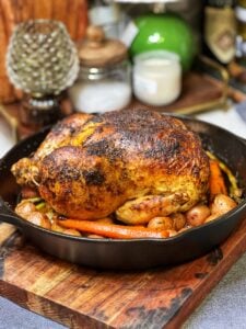 A roasted chicken and vegetables in a cast iron pan.