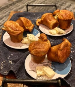 three plates filled each with two Gruyère and black pepper popovers with butter