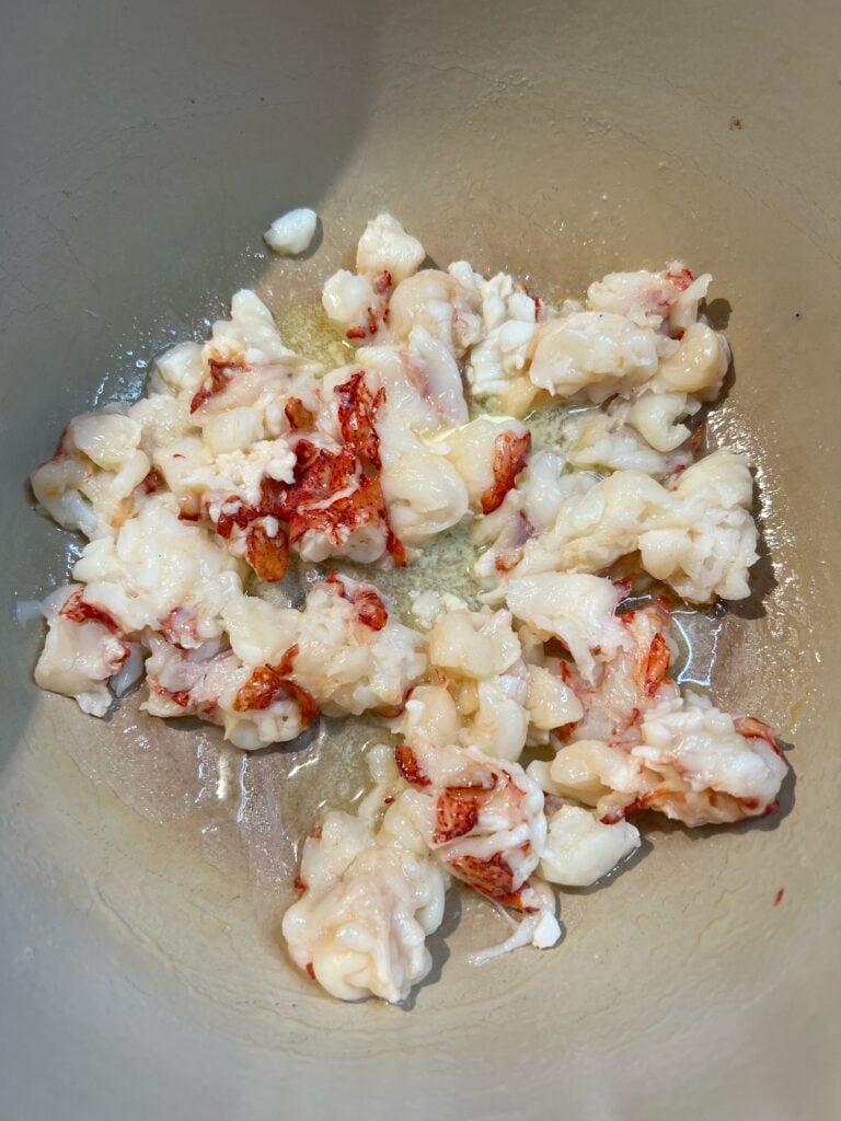 Poaching chunks of uncooked lobster in a pot of melted butter.