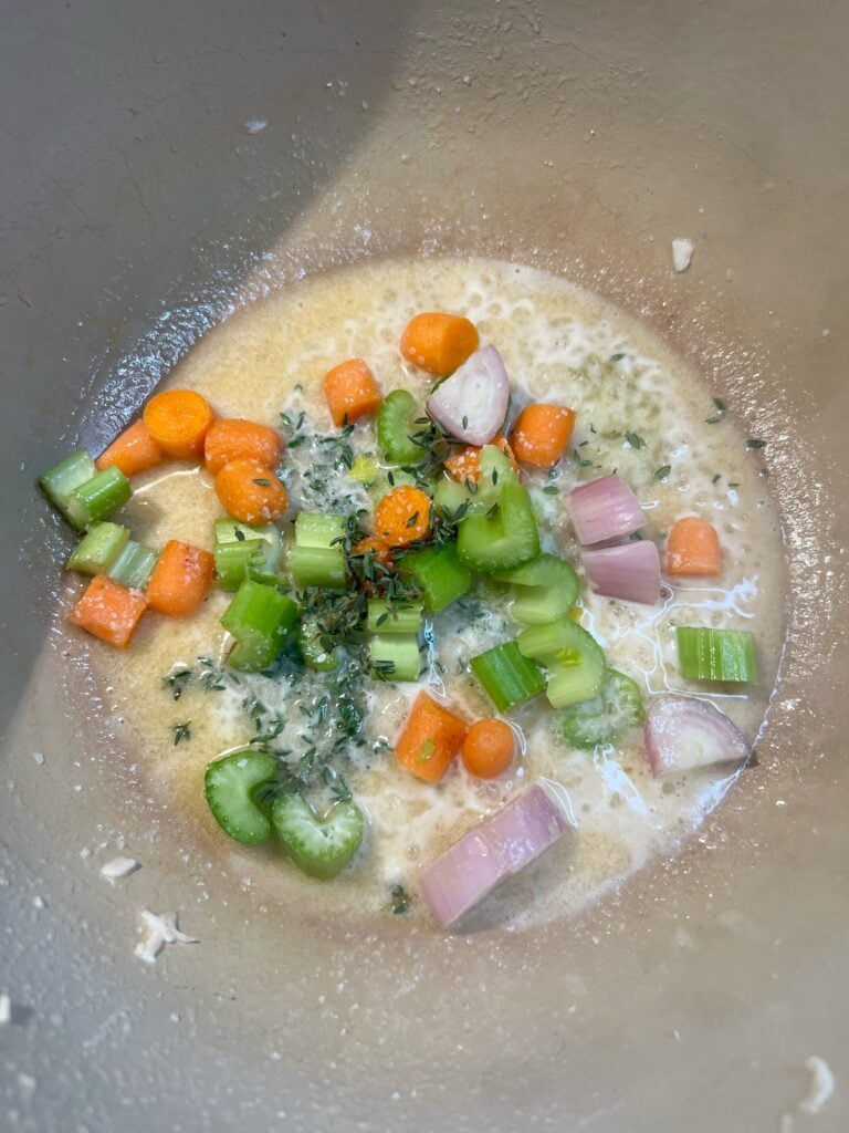 Roughly chopped carrots, celery, shallots and fresh thyme sautéing in butter in a pot.