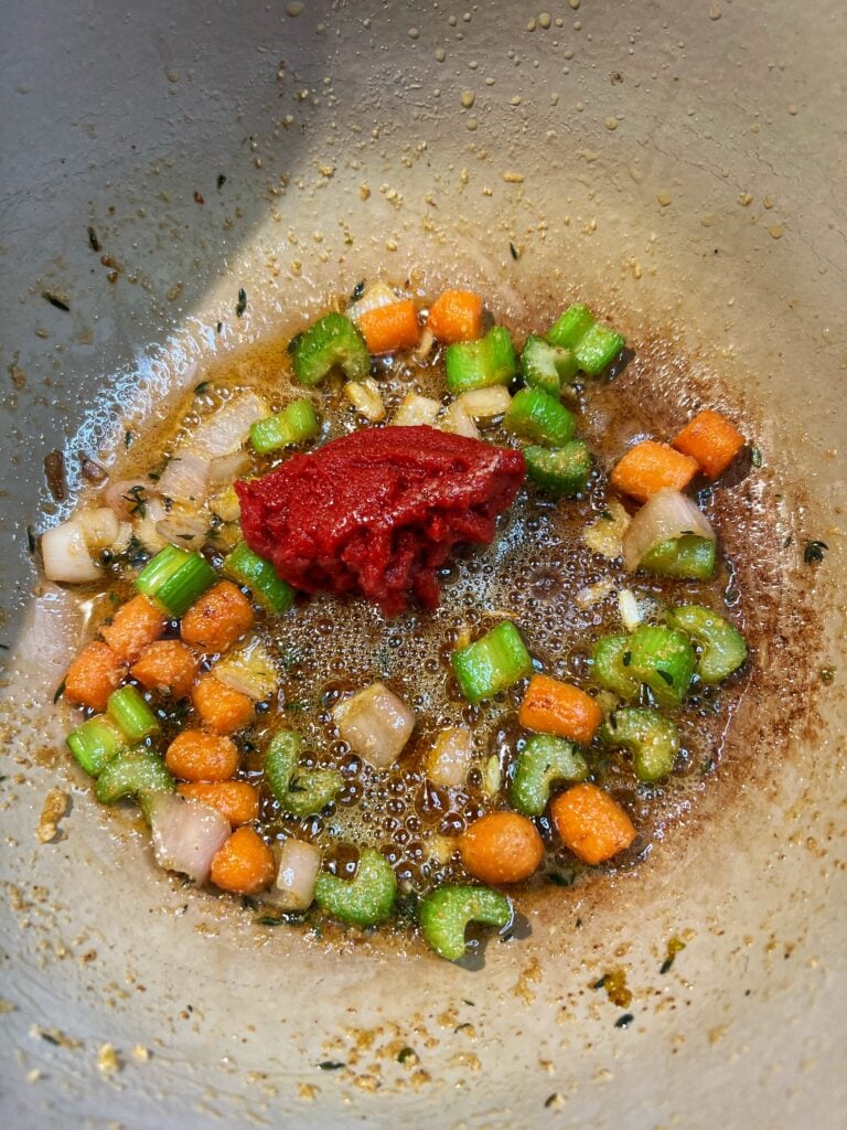 Tomato paste added to a pot of sautéed carrots, celery and shallots for Creamy Lobster Bisque.