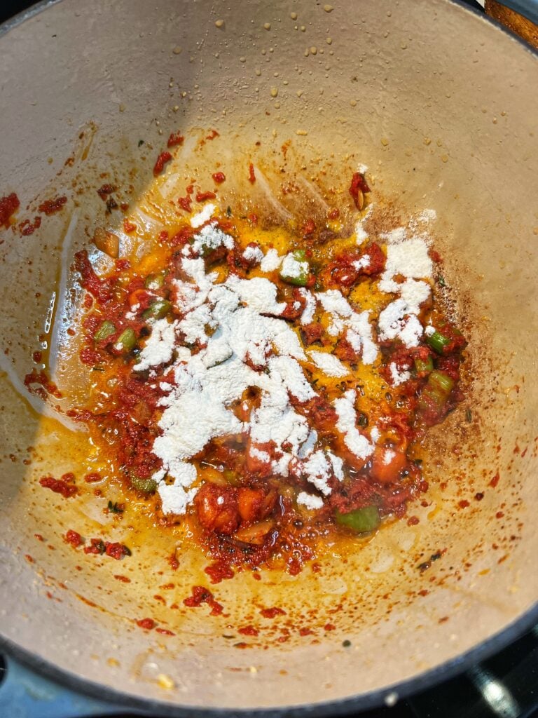 Flour dusted over sautéed vegetables and tomato paste.