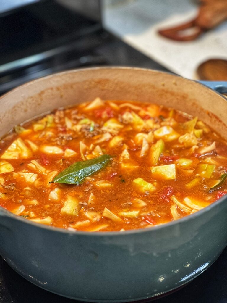 A big blue pot filled with diced cabbage, V-8 juice, ground beef and rice simmering for cabbage roll soup.
