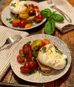 two plates of burrata toast with tomatoes