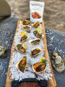 a platter of Korean bbq grilled oysters with a pouch of Kevin's sauce in the background