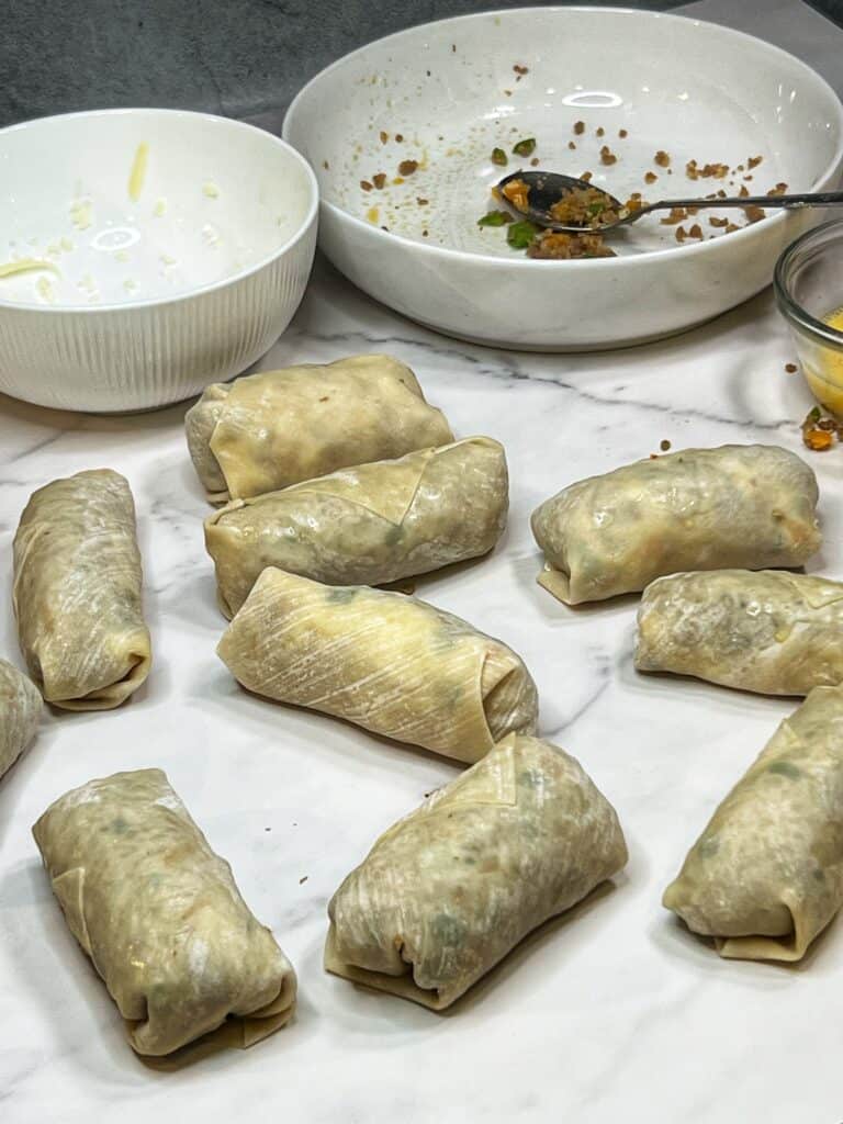 Nine sausage and pepper filled egg rolls.