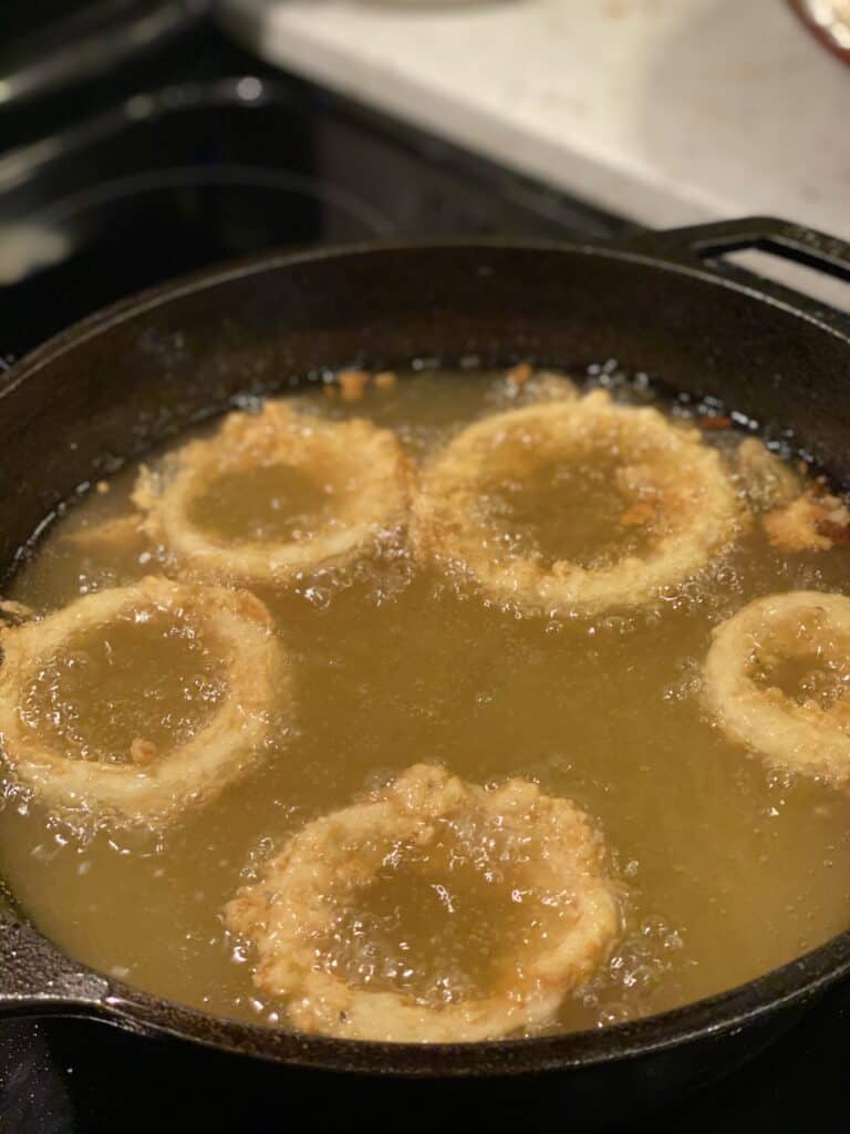 Vidalia onion rings frying in a cast iron pan