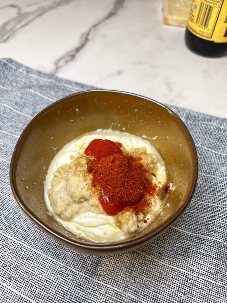 Mayo, horseradish, paprika and Worcestershire sauce in a small brown bowl. The ingredients are not mixed together.