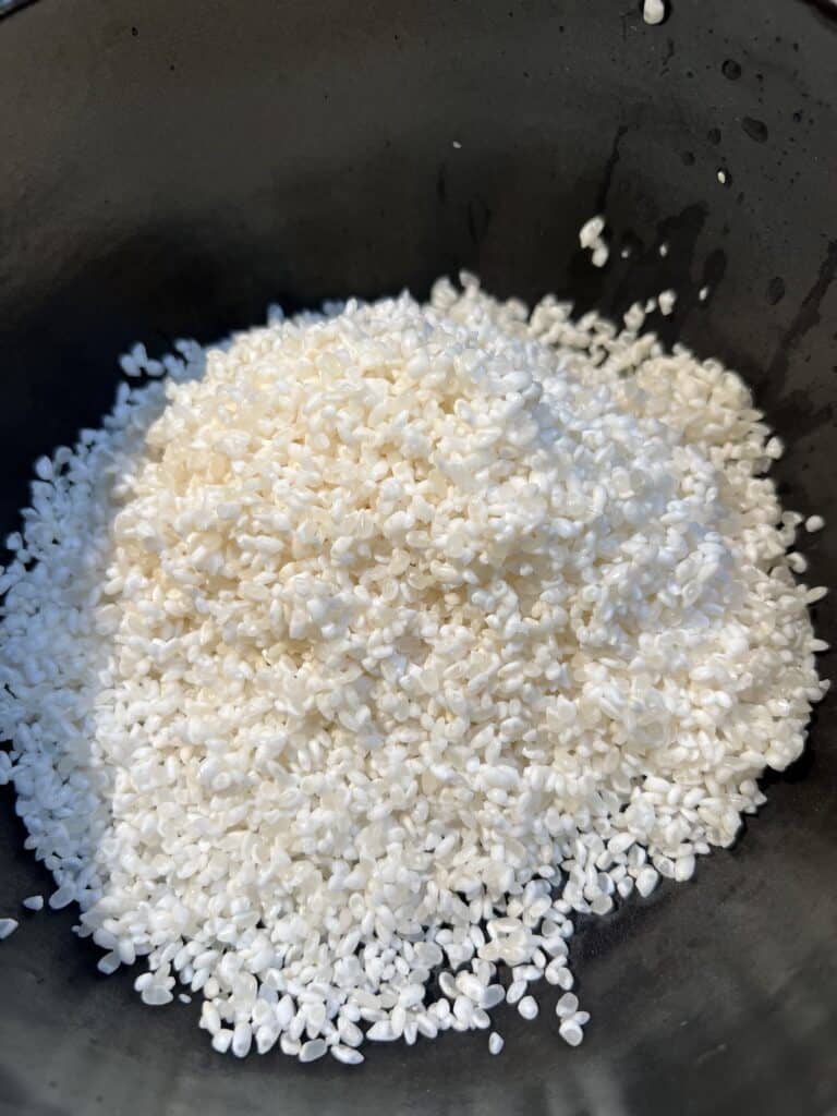 Soaked short-grain rice in a brown bowl.