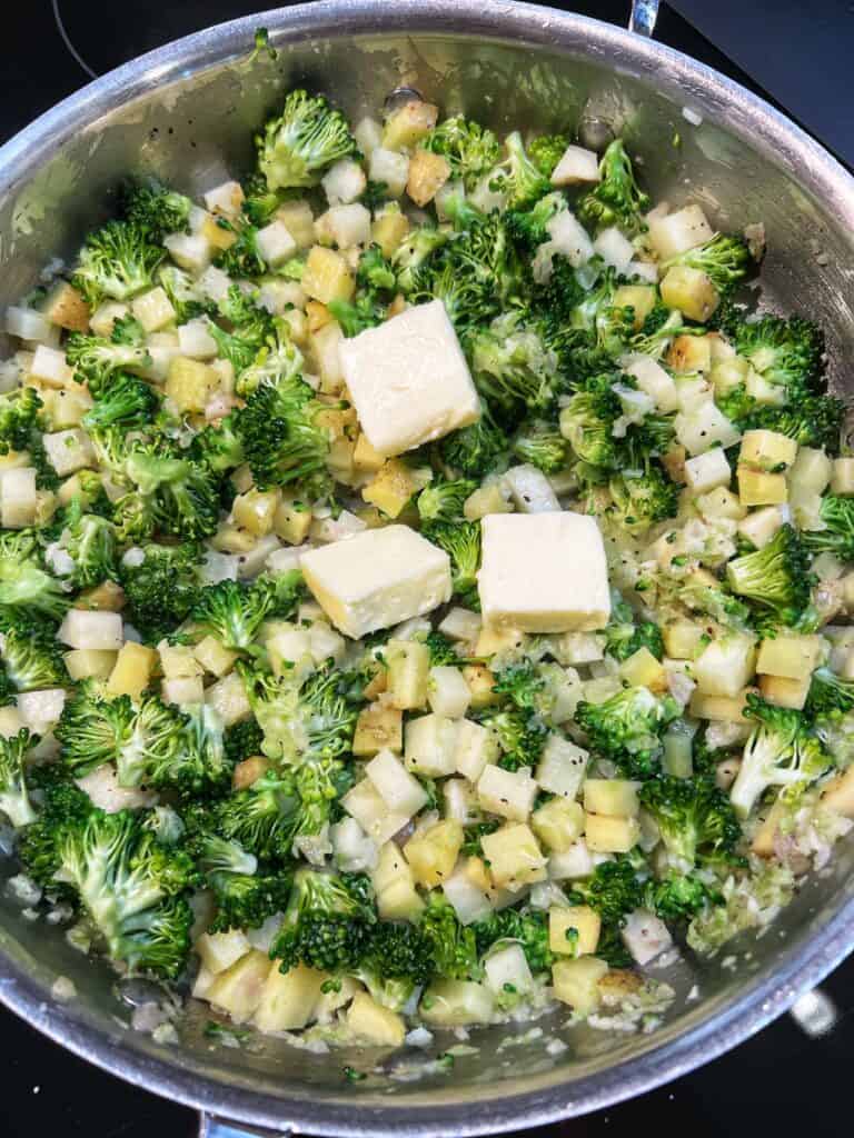 Three tablespoons of butter added to a pan with broccoli and diced potatoes.