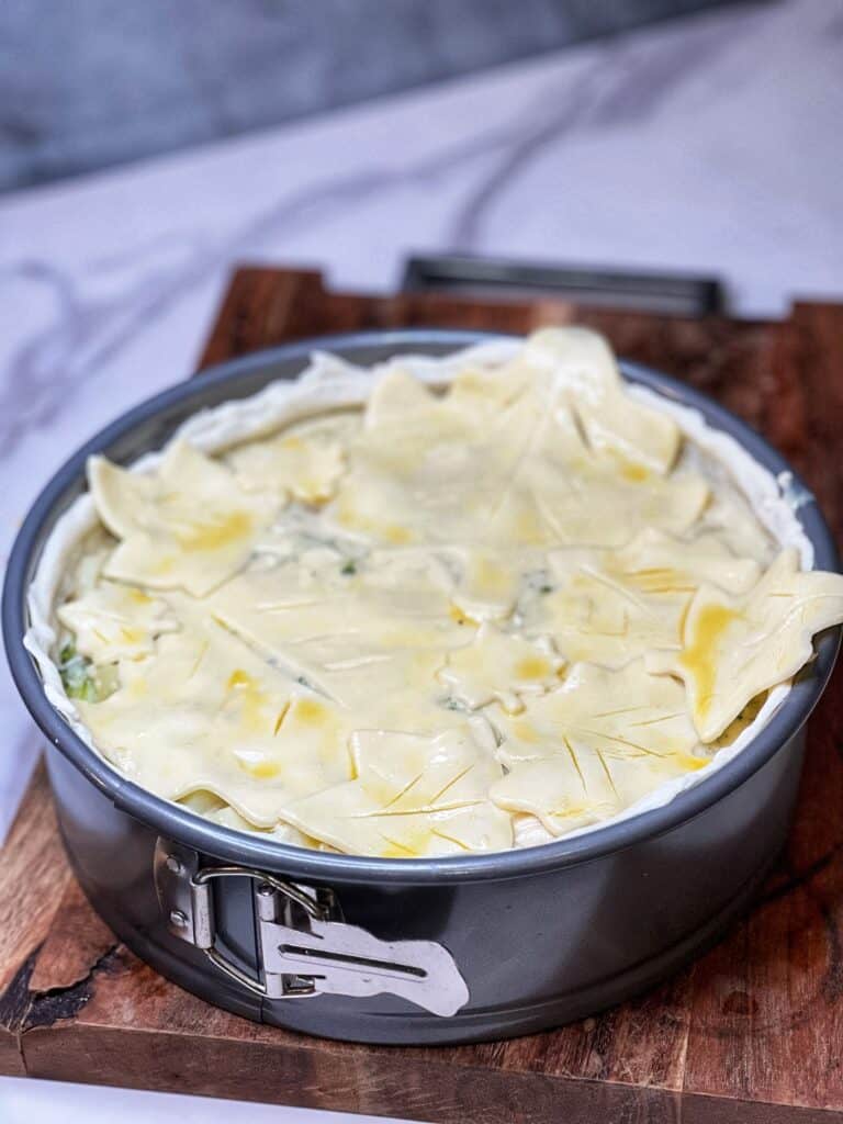 A springform pan filled with creamy chicken and broccoli topped with decorative leaves that were made from pastry dough.