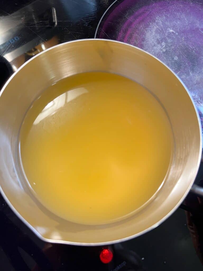 Chicken stock heating in a small pot.