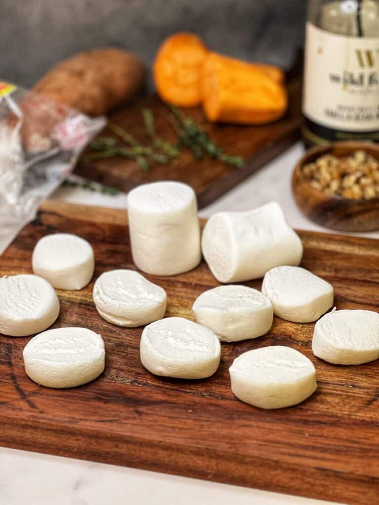 Jumbo marshmallows cut into three pieces sitting on a wooden board.