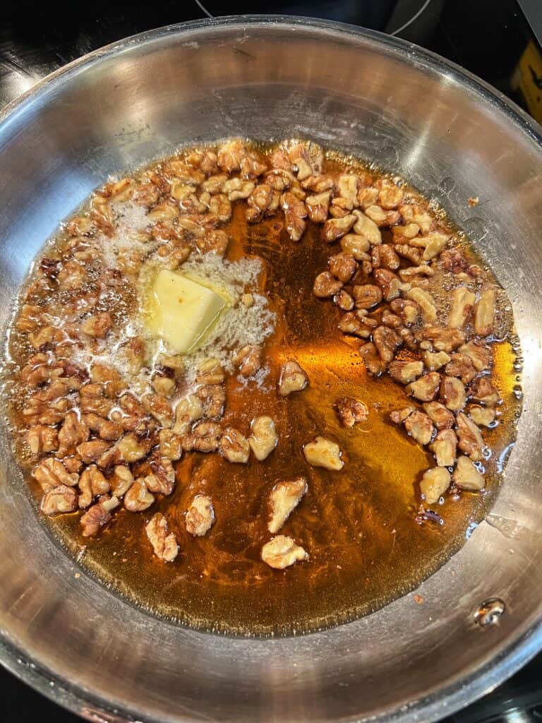 Maple syrup, butter and toasted walnuts in a stainless steel pan.