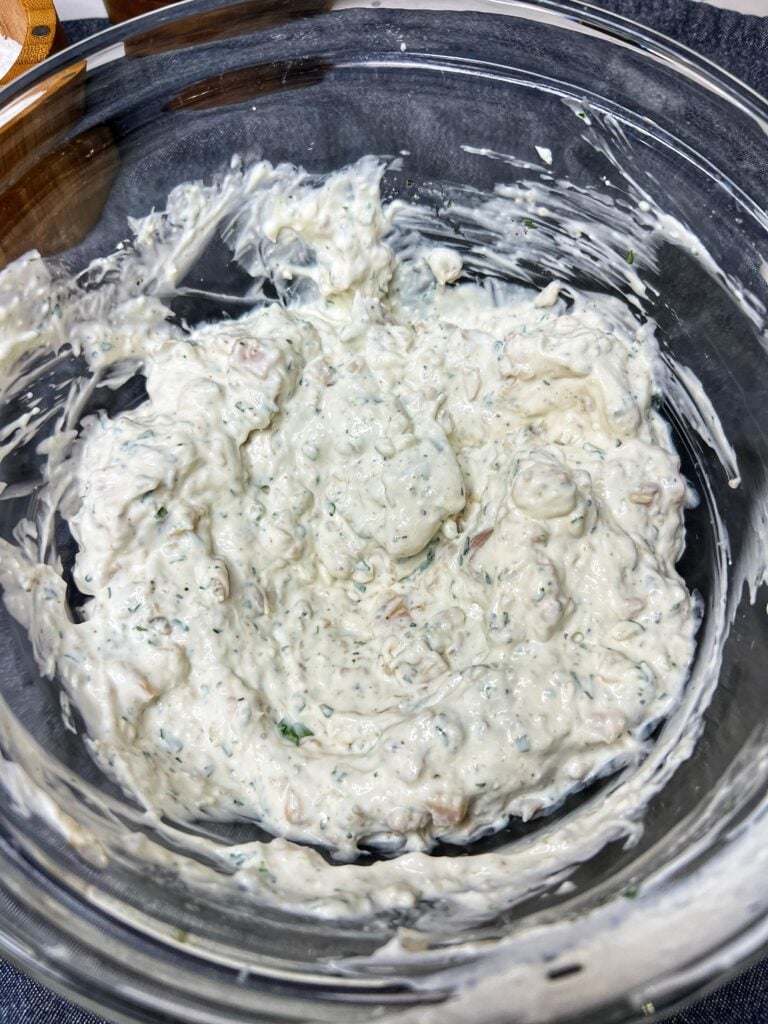 Creamy clam dip in a glass bowl. The dip is cream cheese and sour cream based.