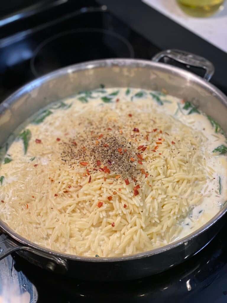 ingredients waiting to be mixed together in a pan for creamy spinach orzo pasta
