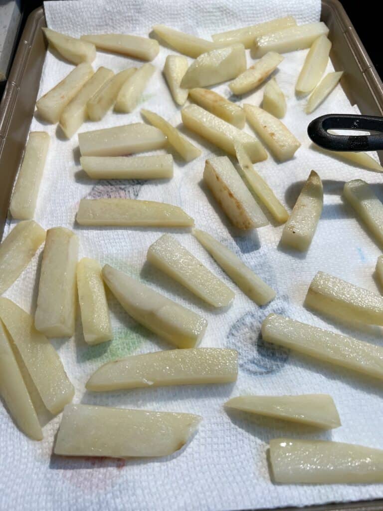 Chips that are draining on paper towels after their first fry for fish and chips.