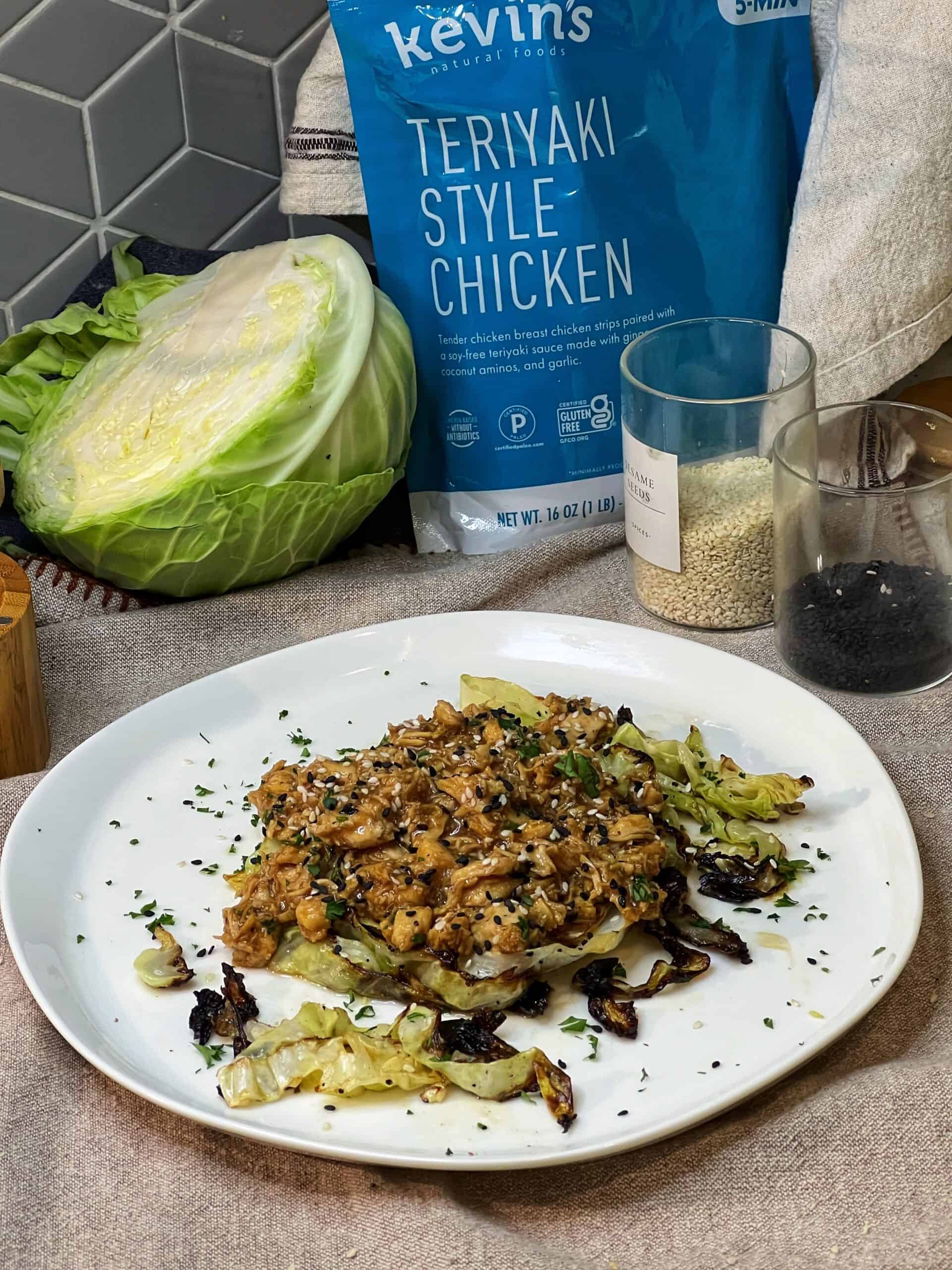 Keto Chicken Teriyaki with Charred Cabbage sitting on a white plate with a half head of cabbage and a package of Kevin's Natural Foods Chicken Style Teriyaki