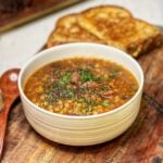 A bowl of easy crockpot lentil soup garnished with fresh parsley.