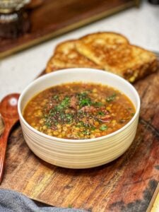 A bowl of easy crockpot lentil soup garnished with fresh parsley.