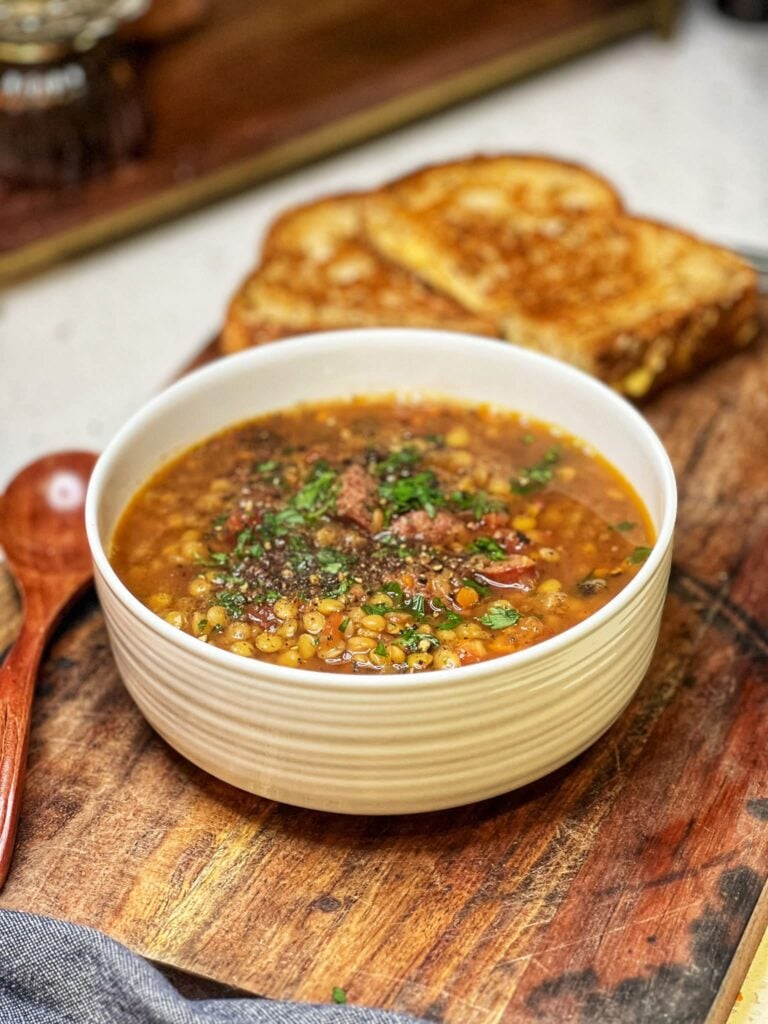 A bowl of easy crockpot lentil soup garnished with fresh parsley.