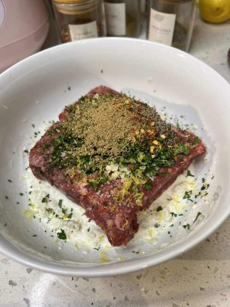Ingredients in a white bowl for lamb meatballs