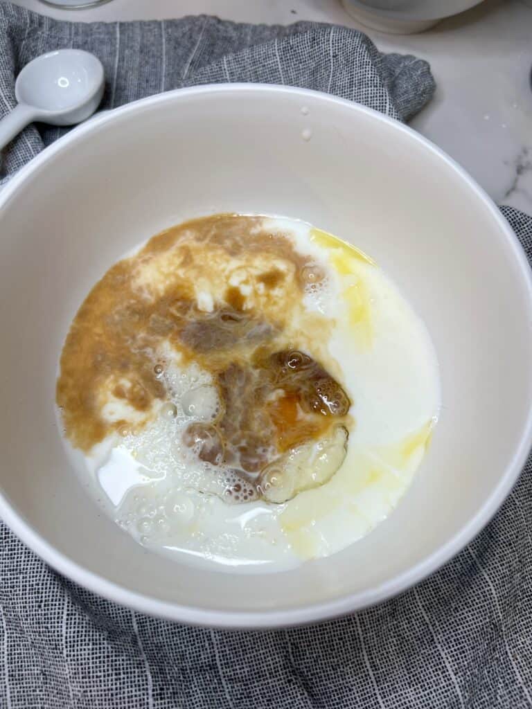 Wet ingredients for super fluffy blueberry pancakes in a bowl. It's a combination of melted butter, sugar, one egg, milk and vanilla.