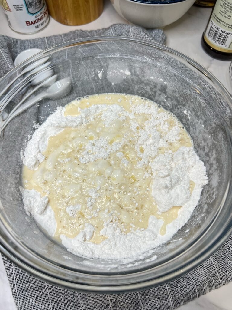 Wet and dry ingredients for pancakes in a glass bowl.