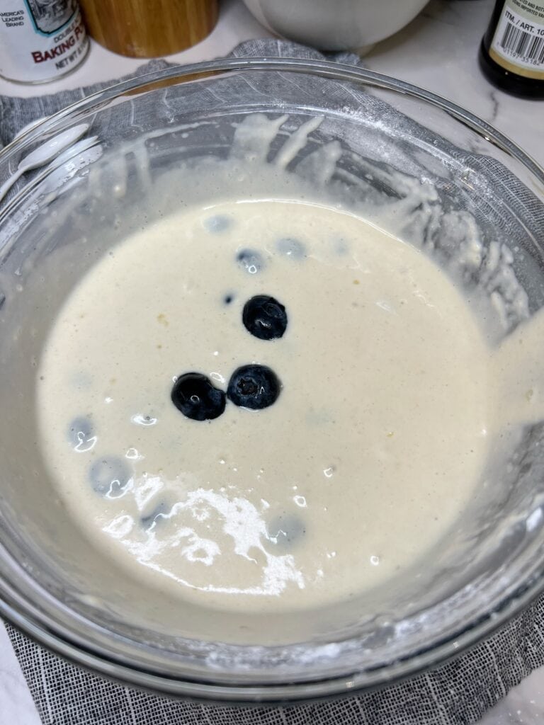 A glass bowl of blueberry pancake batter.