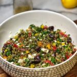 A large bowl filled with lentil salad. This easy lentil salad contains tomatoes, cucumbers, feta cheese and fresh herbs.