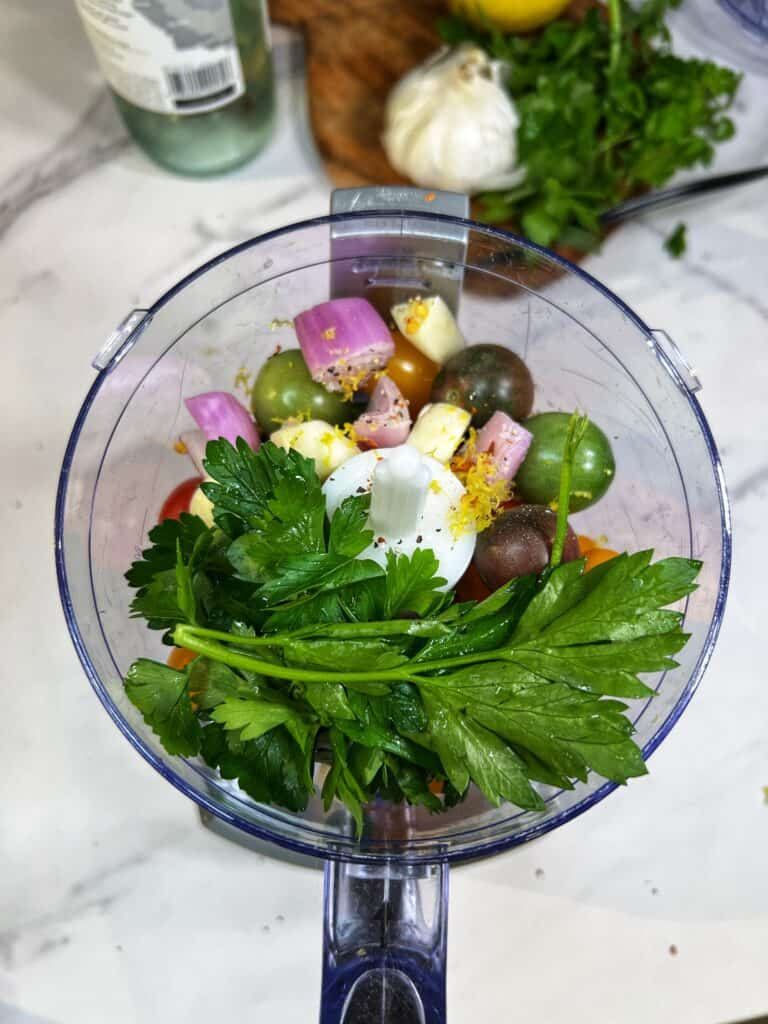 Cherry tomatoes, fresh parsley, roughly chopped shallots, and garlic cloves in a food processor to make the sauce for Strozzapreti Pasta with Clams.