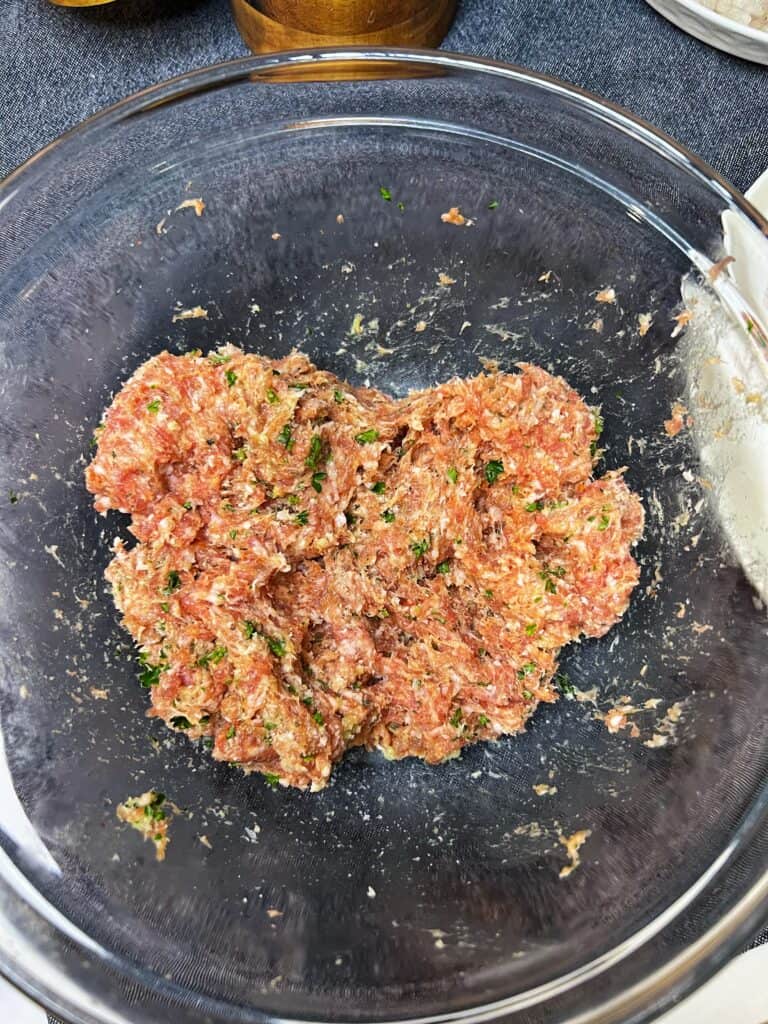 Meatball mix in a glass bowl.