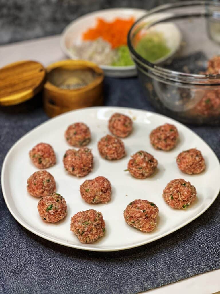 Formed, one-inch meatballs on a white platter.